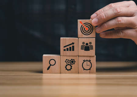 Success Concepts and Business Goals. Hand placed wooden block or selected on the table with action plan icon. Company strategy developmentの写真素材