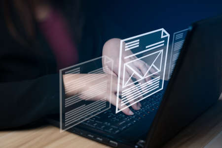 Email Marketing Concept Send an email or internet newsletter that works online. a business woman typing on a laptop on her desk with icon email and letterの写真素材