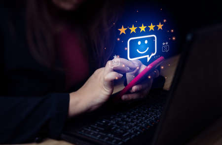 Business woman rated the after-sales service with a mobile phone. Good service of an online store. Concept of customer demand survey. User Ratingの写真素材