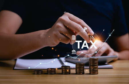 Tax deduction planning concept. Expenses, account, VAT, income tax, and property tax, pay tax. Revenue Department. Individuals calculate annual expenses and taxes. with a pile of coins on the deskの写真素材