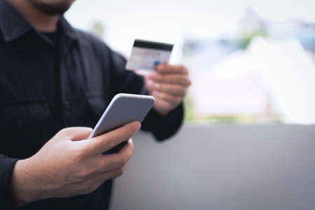 Concept of online payment via credit card. Businessman uses a mobile phone to pay with a credit card through a banking application.の写真素材