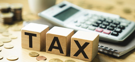 Tax Concept Image Featuring Wooden Blocks Spelling TAX with Calculator and Coins, Representing Financial Planning, Accounting, Budgeting, and Revenue Management for Businesses and Individualsの写真素材