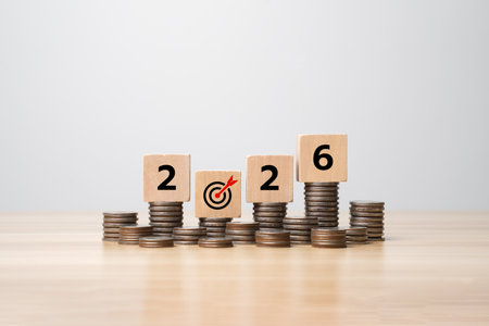 Saving money and financial planning concept for 2026, wooden cubes with year numbers on stacks of...