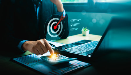 Businessman using calculator with laptop and financial report, target achievement, business planning, budget management, financial analysis, and goal setting strategy conceptの写真素材