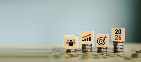 Wooden blocks on stacked coins showing business team, growth chart, target goal, and the year 2026,...