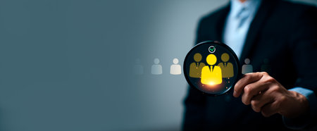 Business professional holding magnifying glass highlighting selected candidate icon, illustrating...