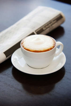 Cup of cappuccino on the table with newspapers on the side, in the morningの写真素材