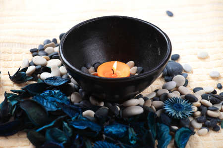 Orange candle in a black bowl and a blue potpourriの写真素材