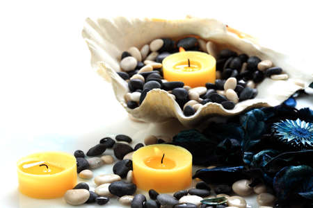 Closeup of yellow candles, blue potpourri and seashell on a white backgroundの写真素材