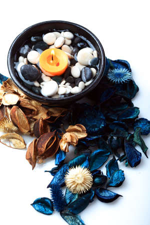 Orange candle in a black bowl with blue and brown potpourriの写真素材