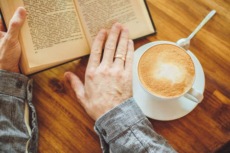 Male hand, coffee and book on the table