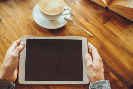Men's hand hold the tablet with coffee