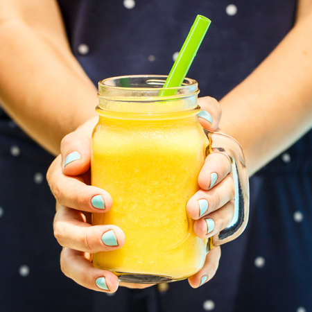 Woman hand holding mango smoothiesの写真素材