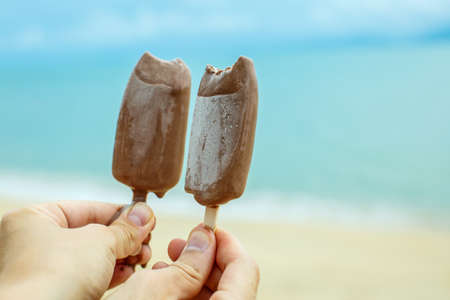 Two hands holding ice creams on a background of the sea