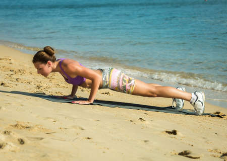 Beautiful fit female fitness model training and working out outside in summer at part of healthy...