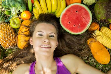 Portrait of a girl lying on the grass with fruits and vegetablesの写真素材