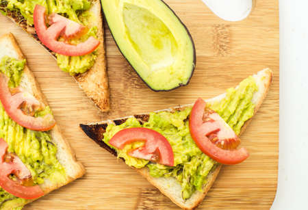 Vegan sandwich with avocado and tomatoes on cutting boardの写真素材