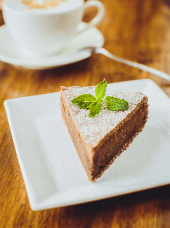 Chocolate cake with a cappuccino on a wooden tableの写真素材