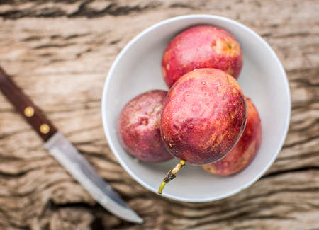 Passion fruit in bowl on a wooden board with knife