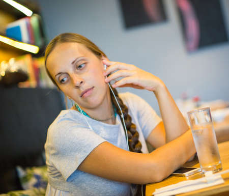Beautiful girl is sitting in the cafe and listening to music on headphones.の写真素材