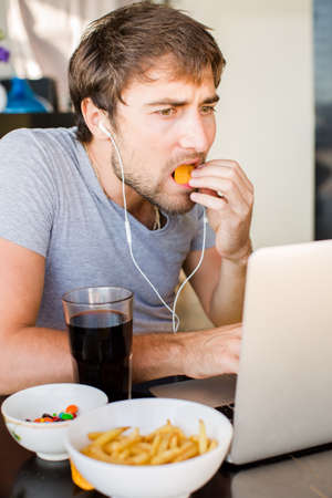 Man working at the computer and eating fast food. Unhealthy Lifestyle.