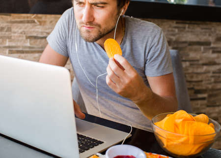 Man working at the computer and eating fast food. Unhealthy Lifestyle.の写真素材