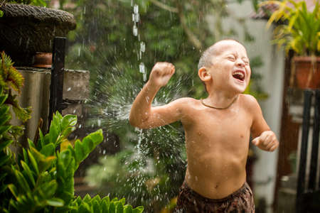 Cute baby boy playing under the rainの写真素材