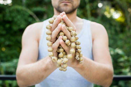 Young man holds a rosary in his hands and pray