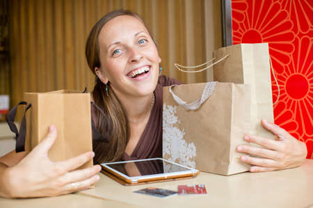 Fashion woman buying online with smart phone and credit card with craft shopping bags beside