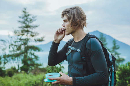 Traveler eat dates against Batur volcano and Agung mountain view at morning from Kintamani, Bali, Indonesiaの写真素材