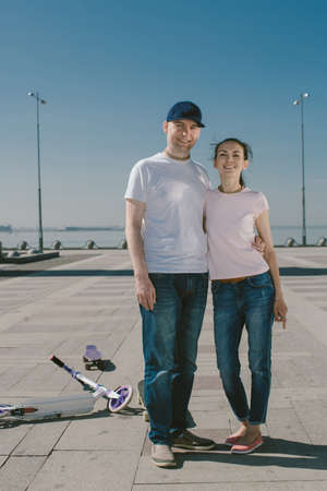 Young Woman Riding a Scooter with her Husband on a Skateboard. Athletic Meeting.