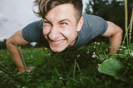 Smiling young man doing push-ups outdoorsの写真素材