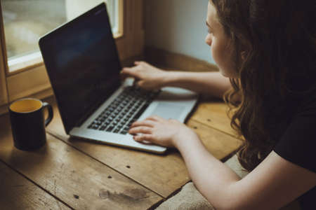 Close up portrait of a young american woman working on laptop and drink coffeeの写真素材