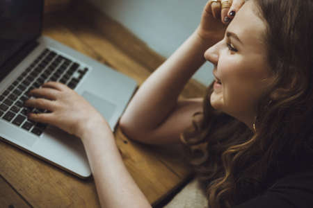 Close up portrait of a young american woman working on laptop and drink coffeeの写真素材