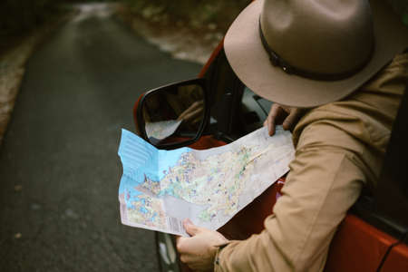 Traveler  man with hat  looking map near car in autumn forestのeditorial素材