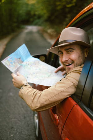 Traveler  man with hat  looking map near car in autumn forestの写真素材