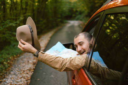 Traveler  man with hat  looking map near car in autumn forest