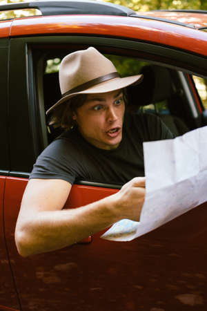 Traveler  man with hat  looking map near car in autumn forestの写真素材