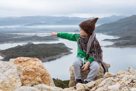 Cute boy in a funny hat sitting on a mountain. Freedom conceptの写真素材