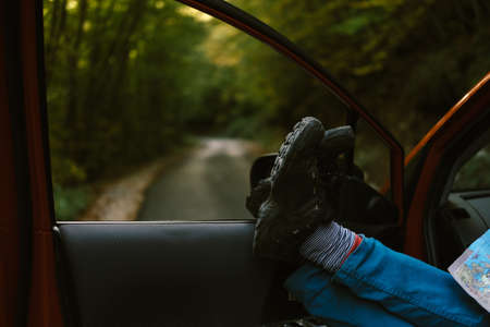 Men's feet with a map in the car in Autumn. Travel conceptの写真素材