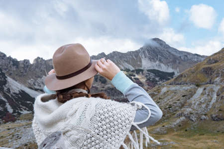 Back view of  young lady with hat and warm poncho on mountain landscape, Durmitor, Montenegroの写真素材