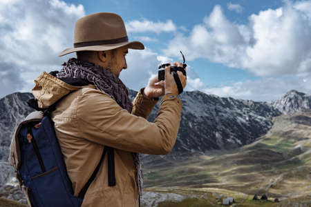 Photographer in hat  taking a picture in autumn mountainsの写真素材