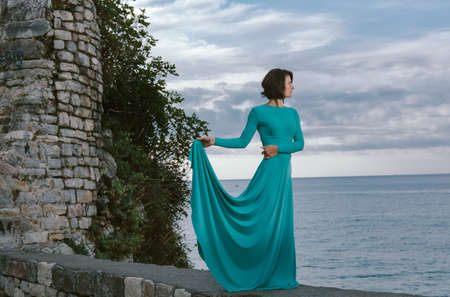 Young brown hair woman wearing elegant fashion dress walking on the old city street Budva, Montenegro.の写真素材