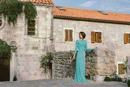Young brown hair woman wearing elegant fashion dress walking on the old city street Budva, Montenegro.の写真素材