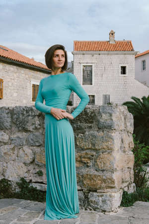 Young brown hair woman wearing elegant fashion dress walking on the old city street Budva, Montenegro.の写真素材