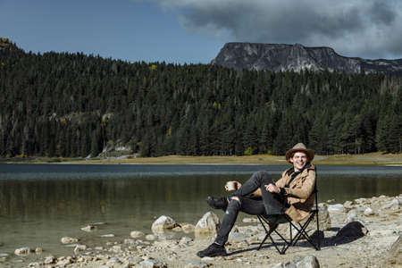 Attractive man in the hat is drinking coffee and enjoying the view of Black Lakeのeditorial素材