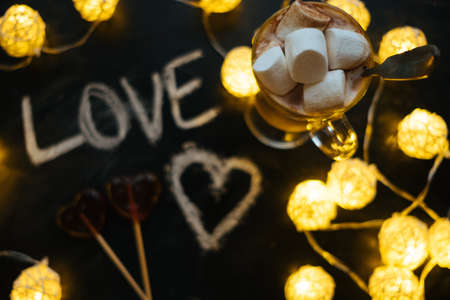 Top view of Heart shape lolipops, word love, hot coffee with marshmallows, lights on background.の写真素材