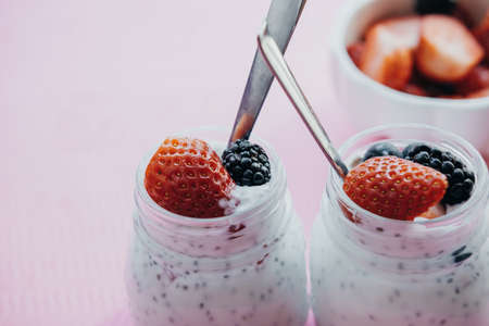 Pudding with chia seeds, yogurt and fresh Berries: Strawberries, blueberries and blackberries in glass jars on pink background. Copy space, toning photoの写真素材