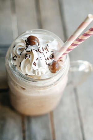 Homemade hot chocolate with whipped cream topping  in retro glass jar (Mason Jar), pink straw and...