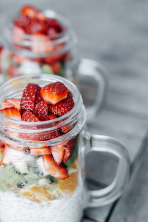 Healthy breakfast with  chia pudding, Strawberry, kiwi, orange served in a Mason Jar on wooden backgroundの写真素材